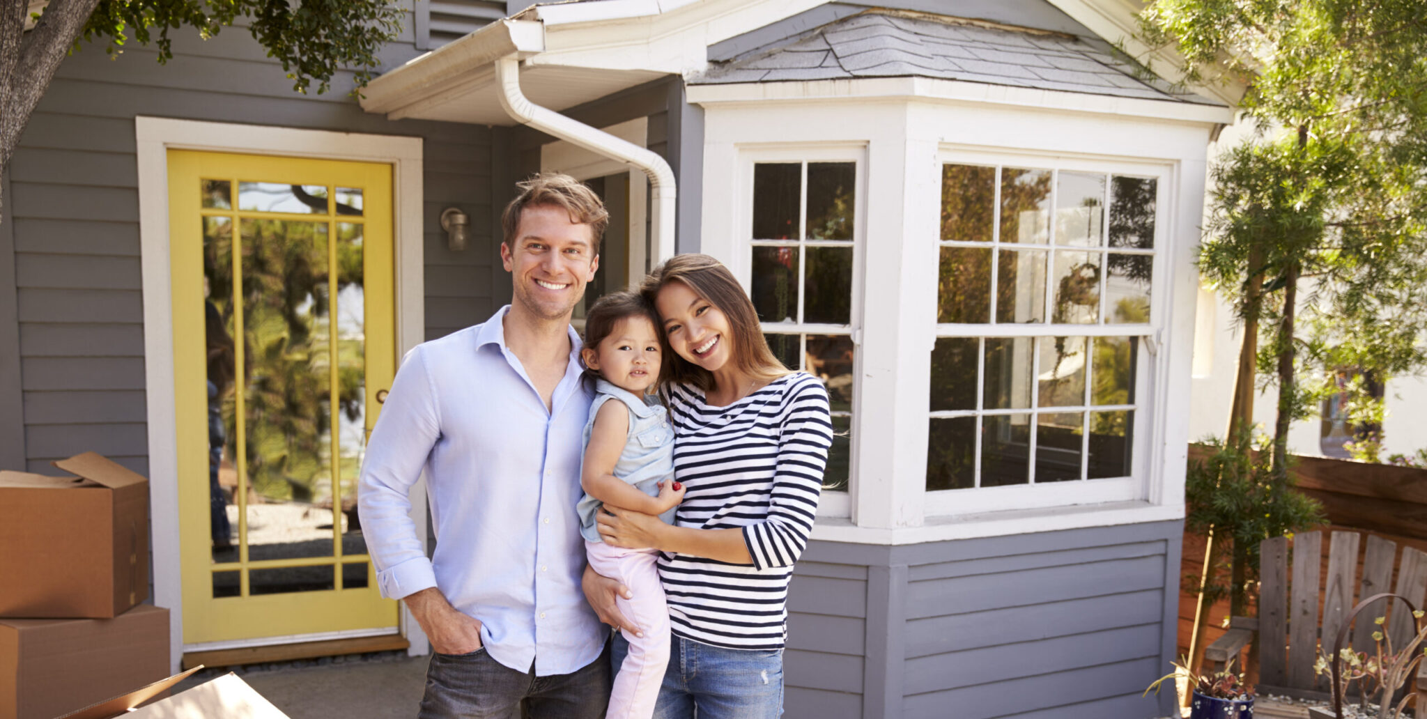 Family with daughter in front of house with boxes