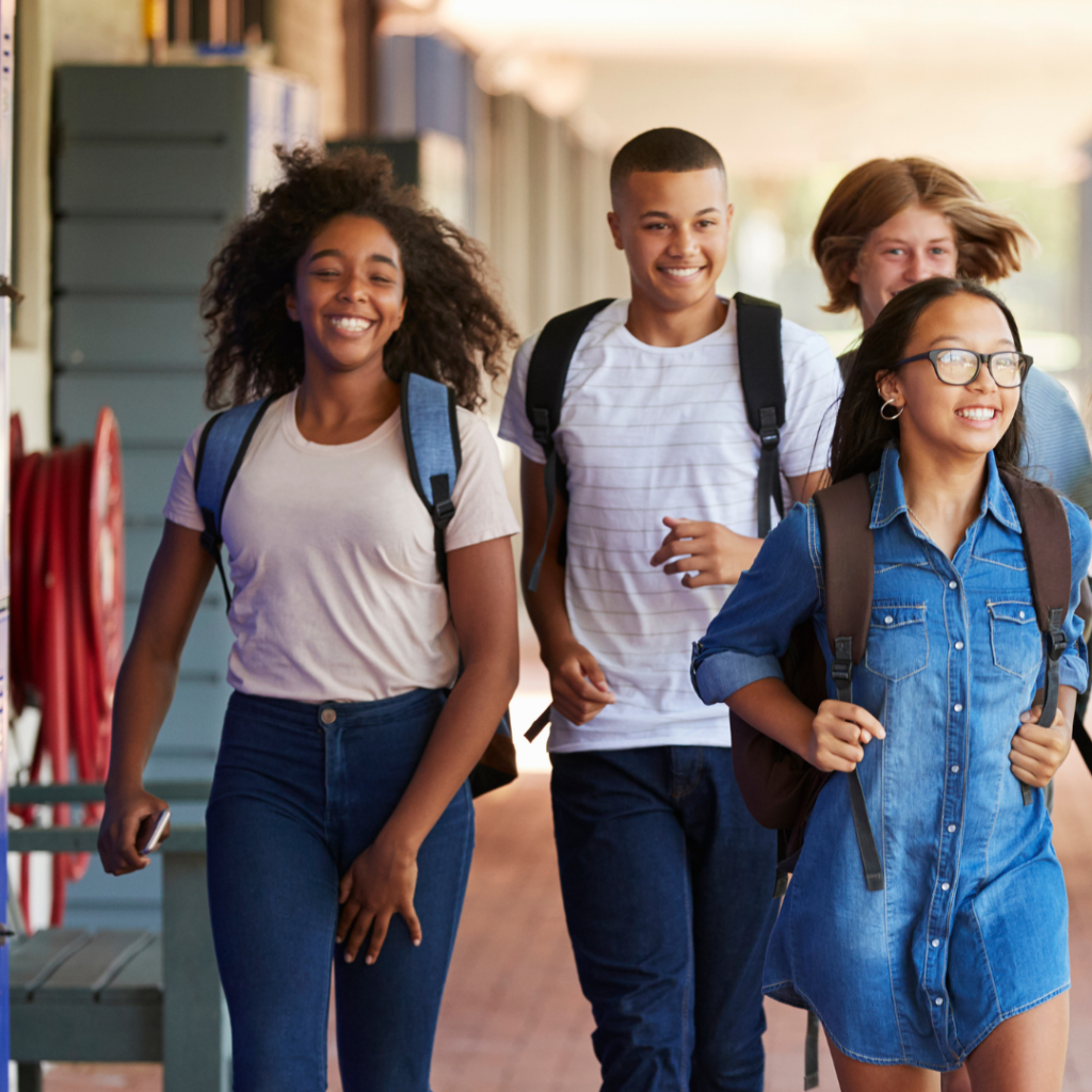 Students walking with backpacks in a school hallway
